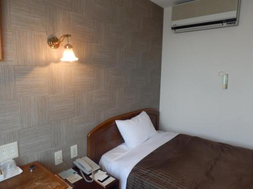 a bedroom with a bed with a lamp and a telephone at Famy Inn Makuhari in Chiba