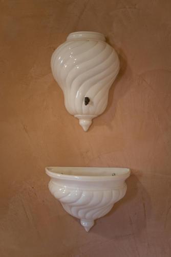 a white vase hanging on a wall with a light at Le Dieci Porte in Alberobello