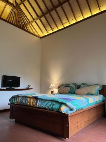 a bedroom with a bed with a tv on the wall at Lombok Riverside Bungalows in Masbagik