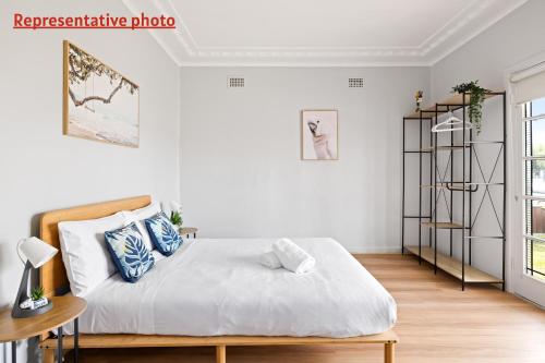 a white bedroom with a bed with blue pillows at Budget Double Room in Belmore - Convenient Stay Near Shops - Shared Bathroom in Sydney