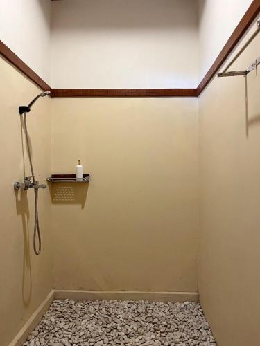 a shower in a bathroom with a wall at Lombok Riverside Bungalows in Masbagik
