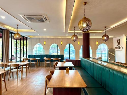 a restaurant with tables and chairs and windows at THE O-ZONE AIRPORT Riviera Lodge in Lat Krabang