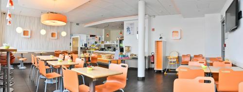 a restaurant with orange chairs and tables and tables and chairs at ibis budget Saint-Quentin Centre Gare in Saint-Quentin