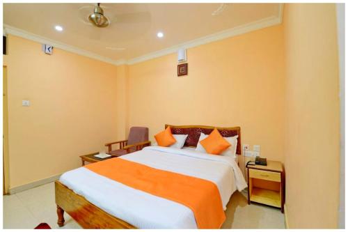 a bedroom with a bed with orange and white sheets at Hotel New Sambit International Near Sea Beach And Jagannath Temple in Puri