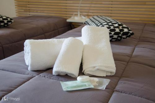 two white towels on a bed with a bottle of soap at Rescio's Rooms in Cavallino di Lecce