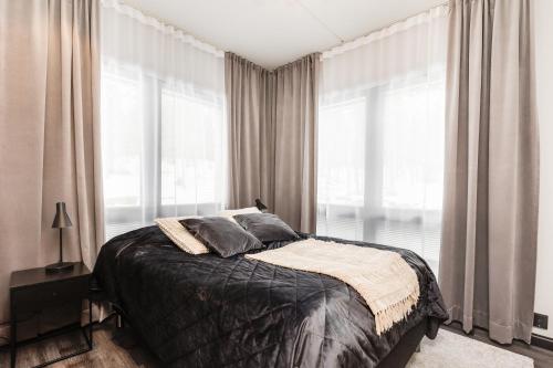 een slaapkamer met een groot bed met ramen bij Levi Cranberry C 13 ski-in ski-out Visit Levi in Levi