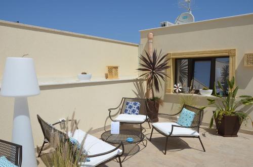 a patio with chairs and tables and a window at RIAD Comfort Rooms in San Vito lo Capo