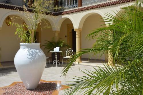 a large white vase sitting in a courtyard with plants at RIAD Comfort Rooms in San Vito lo Capo