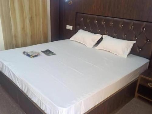 a large white bed with two books on it at The Shloka Badrinath By StayApart in Badrīnāth
