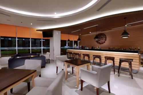 a restaurant with tables and chairs and a bar at Harper MT Haryono by ASTON in Jakarta