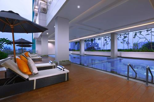 a swimming pool with a bench and an umbrella at Harper MT Haryono by ASTON in Jakarta