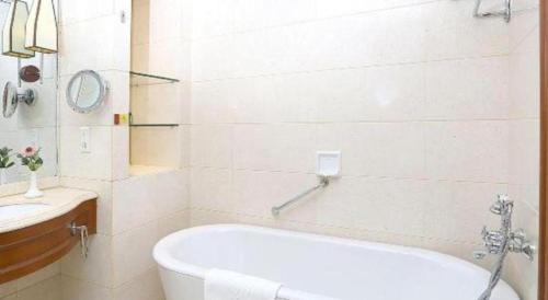 a white bathroom with a tub and a sink at Regency Hotel in Shantou