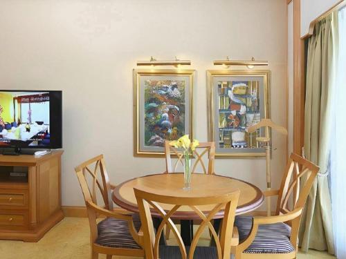 a dining room with a table and chairs and a television at Regency Hotel in Shantou