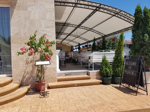 a patio with a table and chairs and a sign at семеен хотел Прованс Ахелой in Aheloy