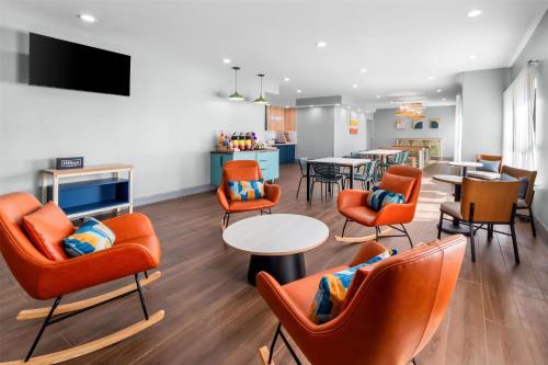 a waiting room with orange chairs and a table at Spark By Hilton Corpus Christi Southeast in Corpus Christi