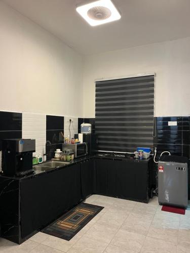 a kitchen with black counters and a counter top at De'Putera Homestay in Batu Pahat