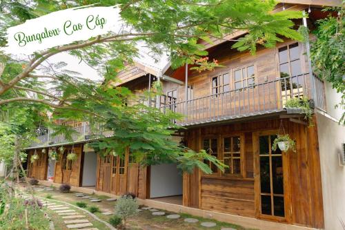 a wooden house with a balcony on the side of it at Cafe cắm trại Đồng Gió Phước Hải in Xã Long Mỹ