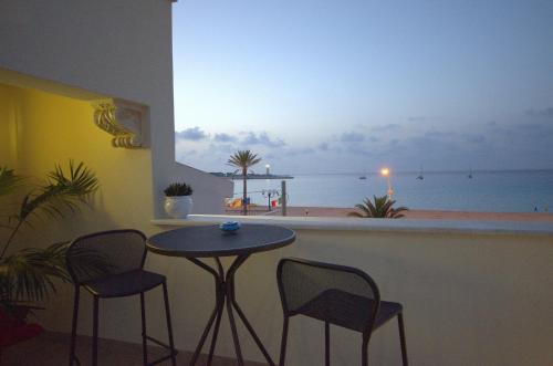 a table and chairs in a balcony with a view of the ocean at RIAD Comfort Rooms in San Vito lo Capo