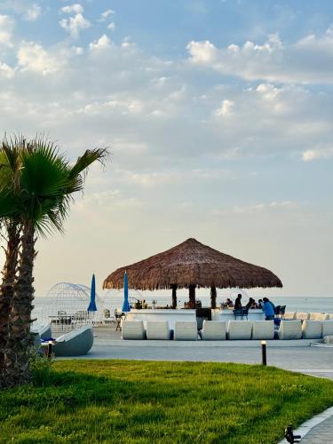 a beach with a large straw umbrella and chairs at Caspi Mayr in Baku