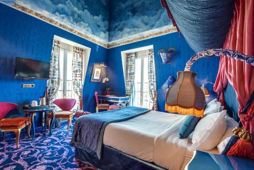 - une chambre avec des murs bleus, un lit et des chaises dans l'établissement La Villa Royale, à Paris