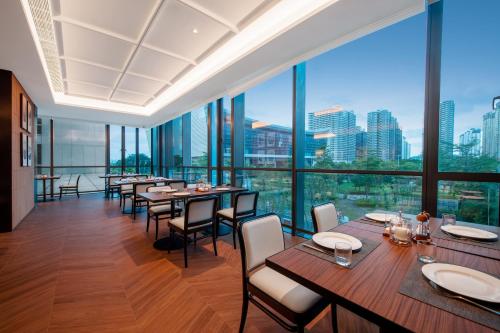 a restaurant with tables and chairs and large windows at Intercity Hotel Shantou CHJ in Shantou
