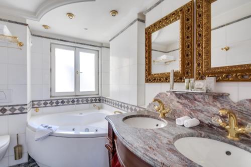 a bathroom with a tub and a toilet and a sink at La Villa Royale in Paris