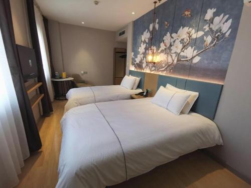 two beds in a hotel room with a painting on the wall at Jinjiang Inn Tianjin Station Jinwan Square in Tianjin