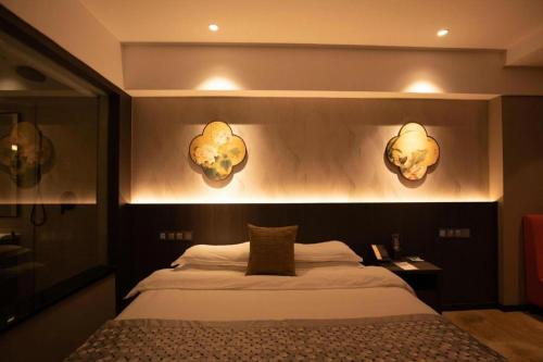 a bedroom with a bed and two lights on the wall at New Friendship Hotel in Luoyang