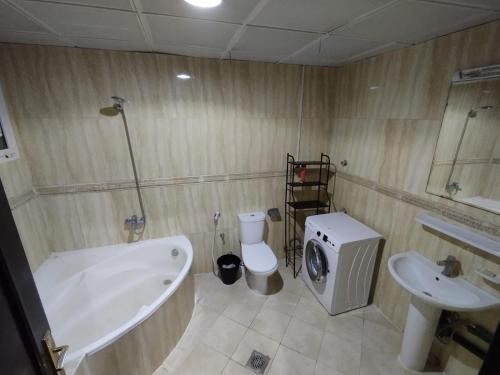 y baño con lavamanos y lavadora. en Ramco Real Estate LLC, en Abu Dabi