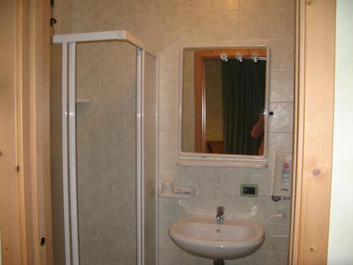 a bathroom with a sink and a shower with a mirror at Hotel Romanda in Lavarone