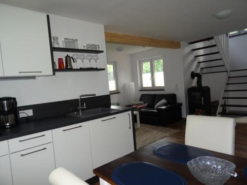 uma cozinha com armários brancos, uma mesa e uma escada em Schwedenhaus im Grünen em Oranienburg