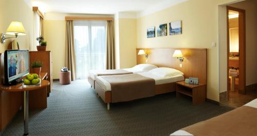 um quarto de hotel com uma cama e uma televisão em Hotel Neptun - Terme & Wellness Lifeclass em Portorož