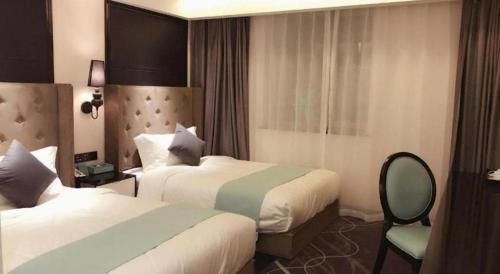 a hotel room with two beds and a chair at Xana Hotelle· Tianjin Railway Station Jinwan Square Binjiang Avenue in Tianjin