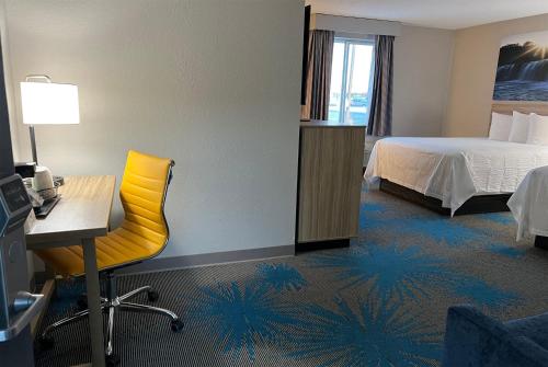 a hotel room with a bed and a desk and a yellow chair at Days Inn by Wyndham Jamestown in Jamestown