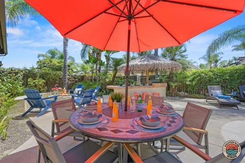 a table with a red umbrella on a patio at The Ultimate Escape Pool, Slide, Gym plus Games! in El Cajon