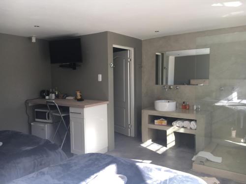 a bedroom with a bed and a sink and a mirror at A Stone's Throw Accommodation in Grahamstown