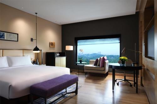 a bedroom with a bed and a couch and a window at Hilton Kuala Lumpur in Kuala Lumpur