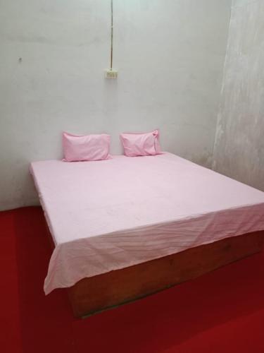 Una cama con sábanas blancas y almohadas rosas. en Hotel Venue, en Kannauj