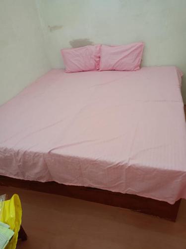 Una gran cama blanca con almohadas rosas. en Hotel Venue, en Kannauj