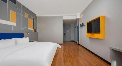 a bedroom with a bed and a tv on a wall at 7 Days Inn Yining Xintiandi in Kipekyüzi