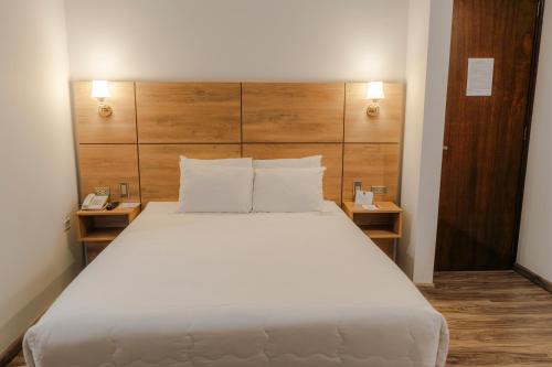 a bedroom with a large white bed with wooden headboard at HOTEL PIEDRA SANTA - Moquegua in Moquegua