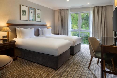 a hotel room with a large bed and a desk at DoubleTree by Hilton Cheltenham-Cotswolds in Cheltenham