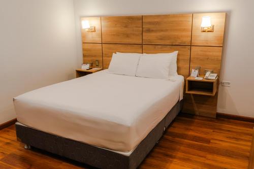 a large bed in a hotel room with two tables at HOTEL PIEDRA SANTA - Moquegua in Moquegua