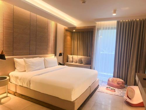 a bedroom with a large white bed and a window at Howard Johnson by Wyndham Pattaya JC in Na Jomtien