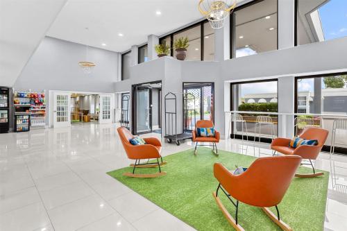a living room with orange chairs and a green rug at Spark by Hilton Des Plaines Chicago O'Hare in Des Plaines