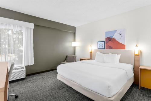 a hotel room with a large white bed and a window at Spark by Hilton Des Plaines Chicago O'Hare in Des Plaines