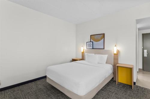 a bedroom with a white bed and a mirror at Spark by Hilton Des Plaines Chicago O'Hare in Des Plaines