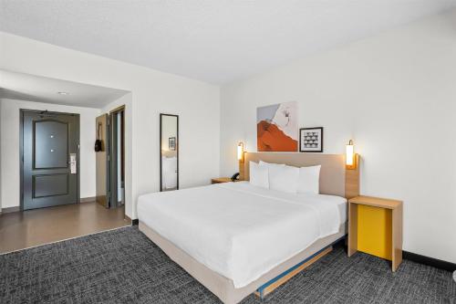 a bedroom with a large white bed and a table at Spark by Hilton Des Plaines Chicago O'Hare in Des Plaines