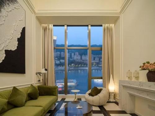 a living room with a green couch and a large window at Ouchen International Sky River Hotel (Monument to the people's Liberation Pedestrian Street Store, Chongqing) in Chongqing