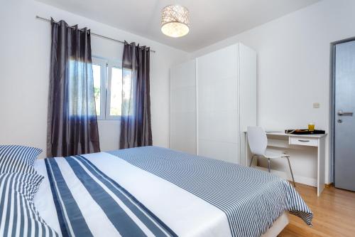ein weißes Schlafzimmer mit einem Bett und einem Schreibtisch in der Unterkunft Holiday Home Iris in Marina